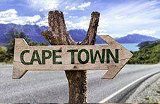 Wooden road sign pointing the way to Cape Town on a mountain road